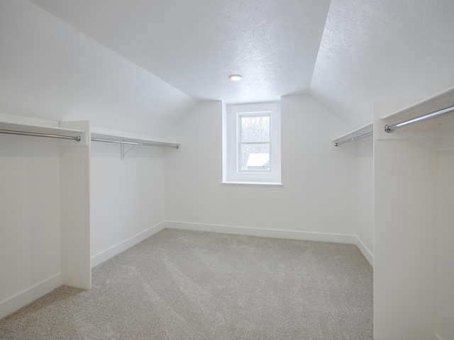 walk in closet with lofted ceiling and light colored carpet