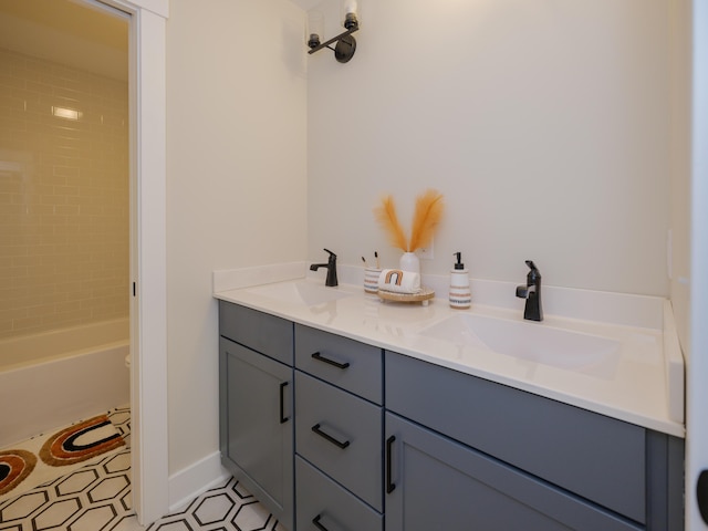 full bath with double vanity, baseboards, and a sink