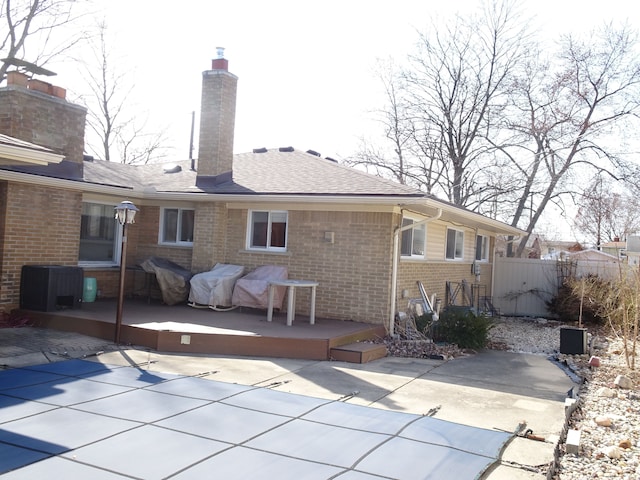 rear view of property featuring a patio, cooling unit, fence, and brick siding