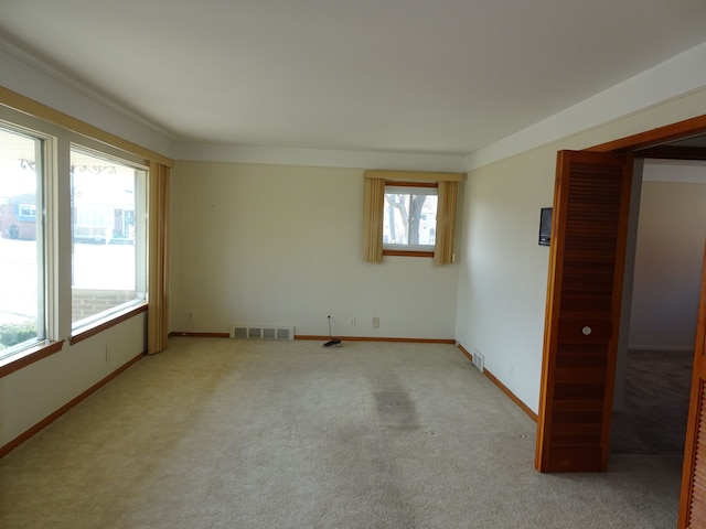 unfurnished room with light colored carpet, visible vents, and baseboards