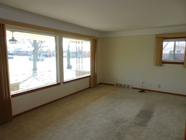 spare room with light carpet, visible vents, and baseboards