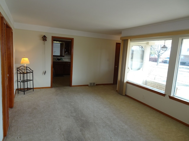 spare room featuring light carpet, visible vents, and baseboards