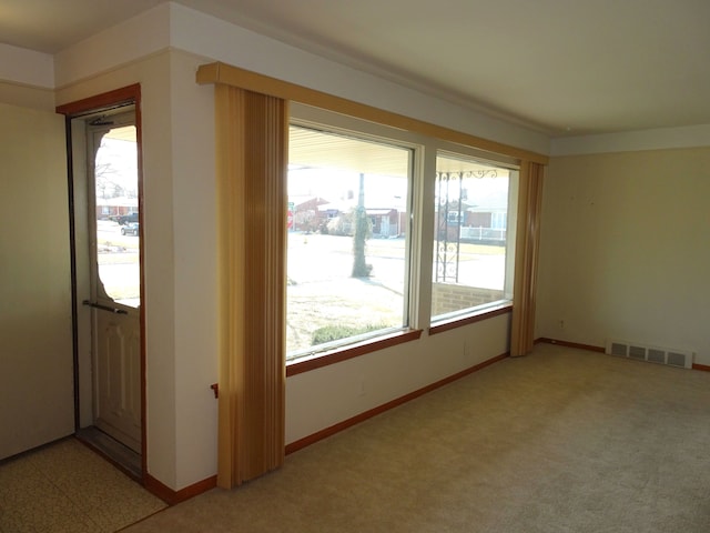 unfurnished room featuring light carpet, visible vents, a healthy amount of sunlight, and baseboards