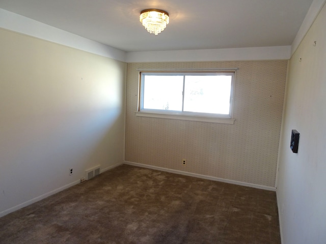 carpeted empty room featuring wallpapered walls, baseboards, and visible vents