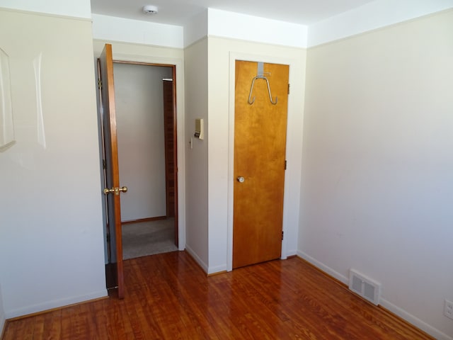 unfurnished room with wood finished floors, visible vents, and baseboards