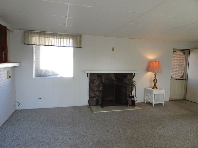 unfurnished living room featuring a paneled ceiling, carpet, and a fireplace