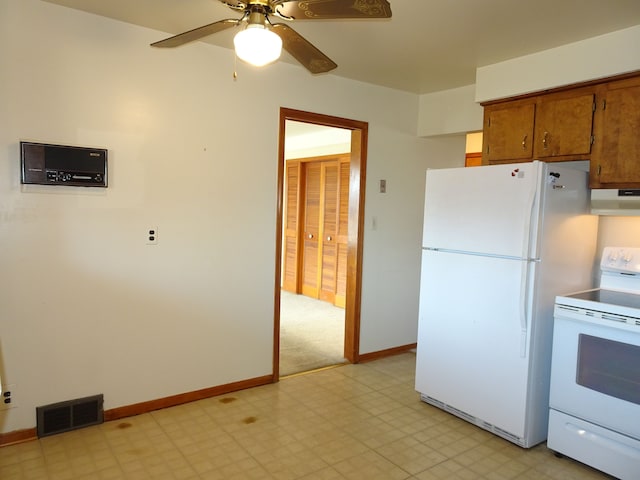 kitchen featuring white appliances, light floors, visible vents, and under cabinet range hood