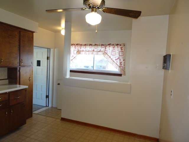 kitchen featuring light floors, light countertops, baseboards, and ceiling fan