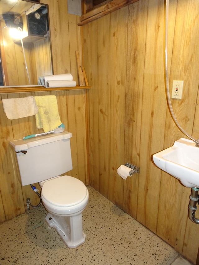 bathroom featuring tile patterned floors, toilet, and wood walls