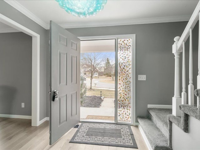 entrance foyer with baseboards, light wood-style flooring, stairs, and crown molding