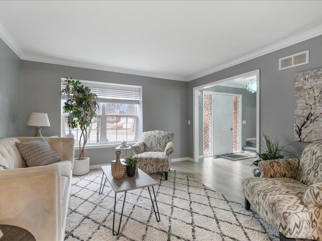 living area with crown molding, wood finished floors, visible vents, and baseboards