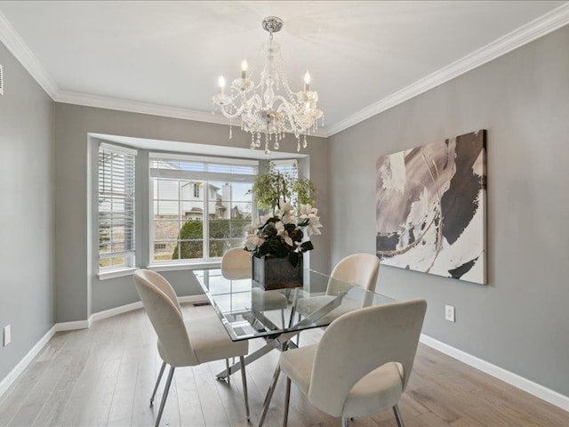 dining room with a chandelier, baseboards, light wood finished floors, and ornamental molding