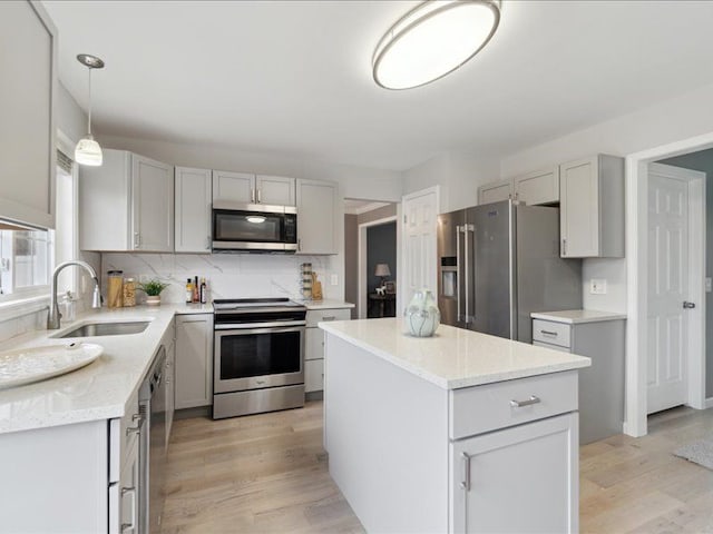 kitchen with light wood-style flooring, a sink, a center island, stainless steel appliances, and decorative backsplash