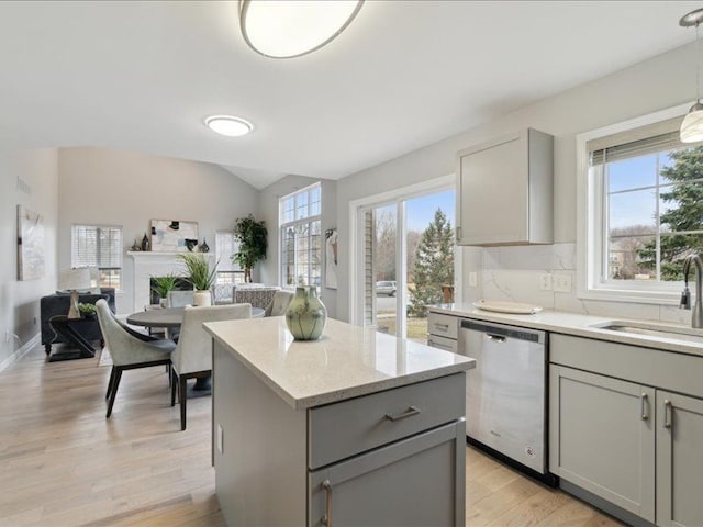 kitchen with a sink, a kitchen island, stainless steel dishwasher, and gray cabinets