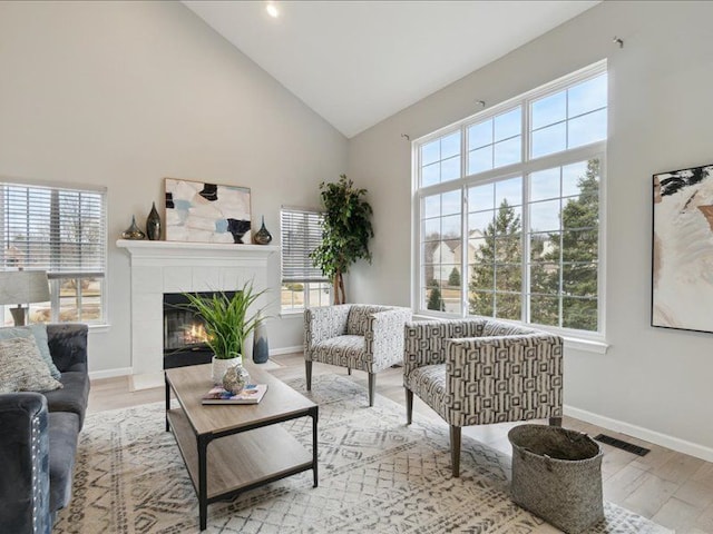 living area featuring high vaulted ceiling, a healthy amount of sunlight, and a tiled fireplace