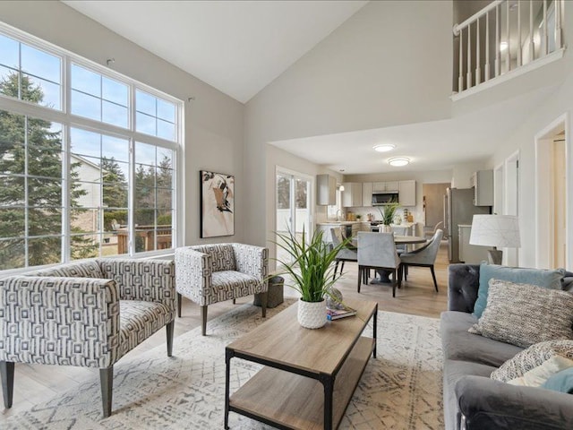 living room with high vaulted ceiling and light wood-style floors