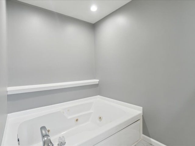 full bathroom featuring baseboards and a whirlpool tub