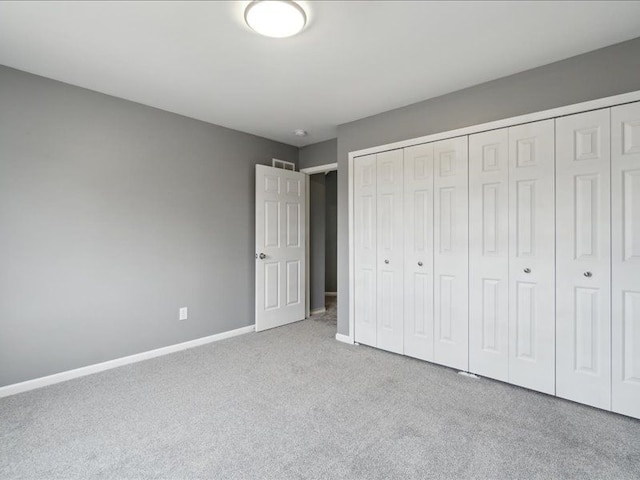 unfurnished bedroom with a closet, visible vents, baseboards, and carpet floors