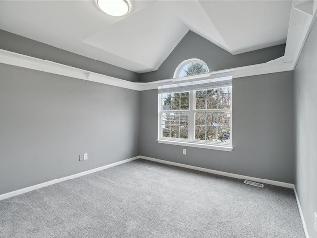 carpeted empty room with visible vents, baseboards, and vaulted ceiling