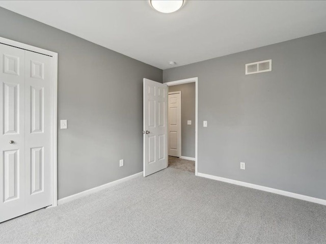 unfurnished bedroom featuring a closet, visible vents, baseboards, and carpet floors