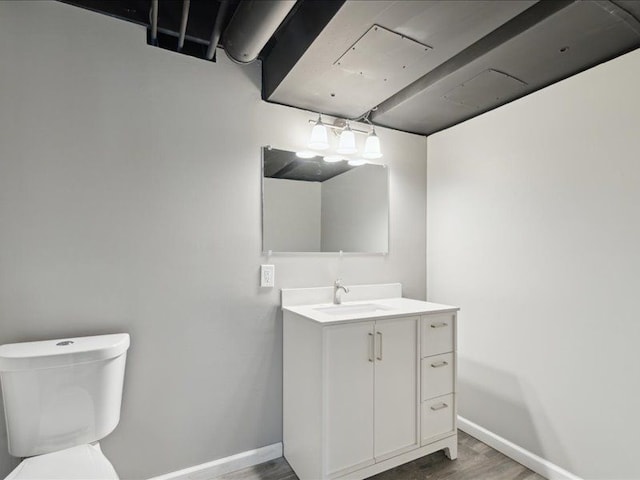 half bathroom featuring baseboards, toilet, wood finished floors, and vanity