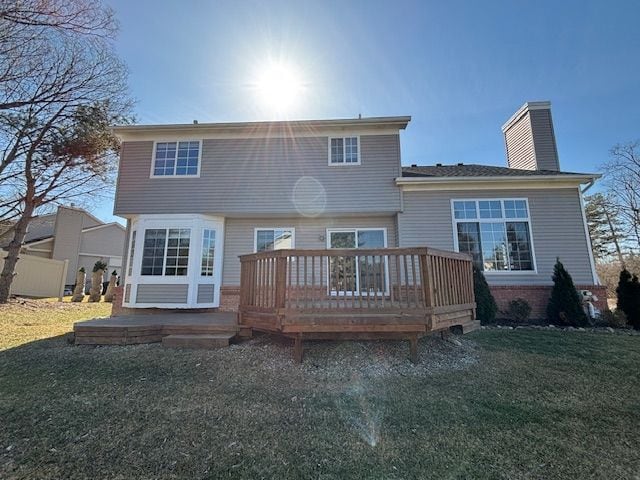 back of property with brick siding, a lawn, a deck, and a chimney