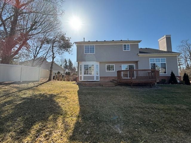 rear view of house with a yard, fence, a chimney, and a wooden deck