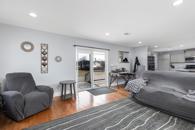 living room with recessed lighting, visible vents, baseboards, and light wood-style floors