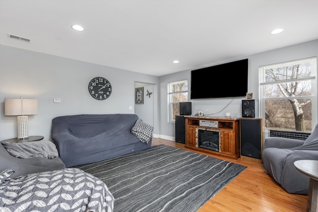 living room with recessed lighting, visible vents, baseboards, and light wood finished floors