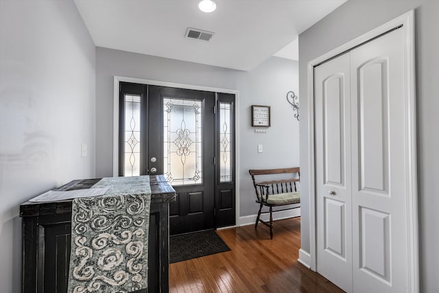 foyer with dark wood finished floors, visible vents, and baseboards