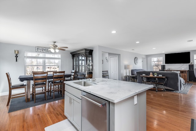 kitchen with a kitchen island with sink, dishwasher, light wood-style flooring, and a healthy amount of sunlight