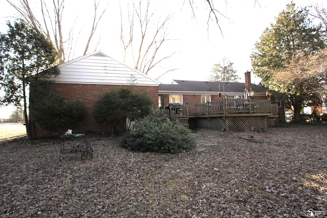 rear view of house with brick siding, a chimney, and a deck