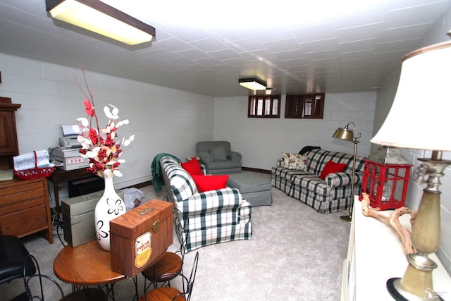 carpeted living area featuring concrete block wall