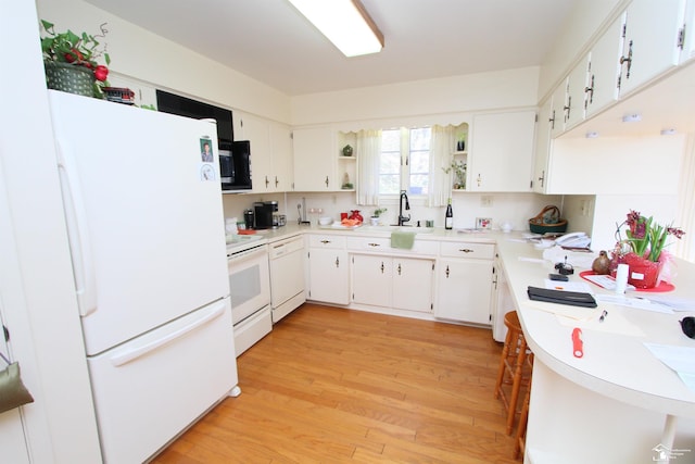 kitchen with light wood finished floors, open shelves, light countertops, white appliances, and a sink