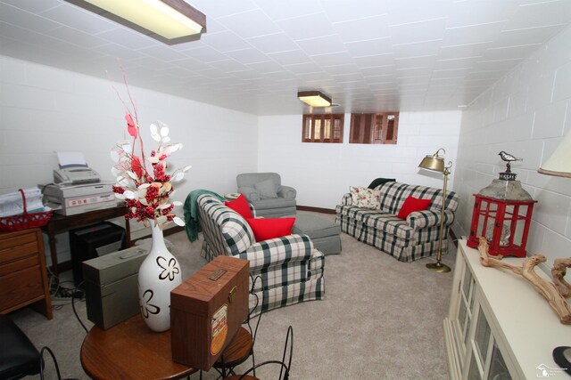 carpeted living room with concrete block wall