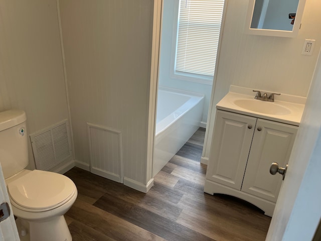 full bathroom featuring visible vents, a washtub, toilet, wood finished floors, and vanity