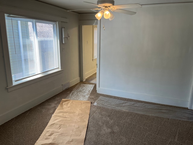 carpeted spare room featuring visible vents, baseboards, and ceiling fan