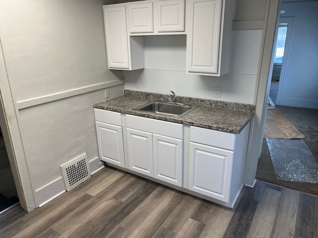 kitchen featuring a sink, visible vents, dark countertops, and white cabinets