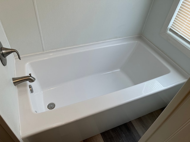 full bath featuring a tub and wood finished floors