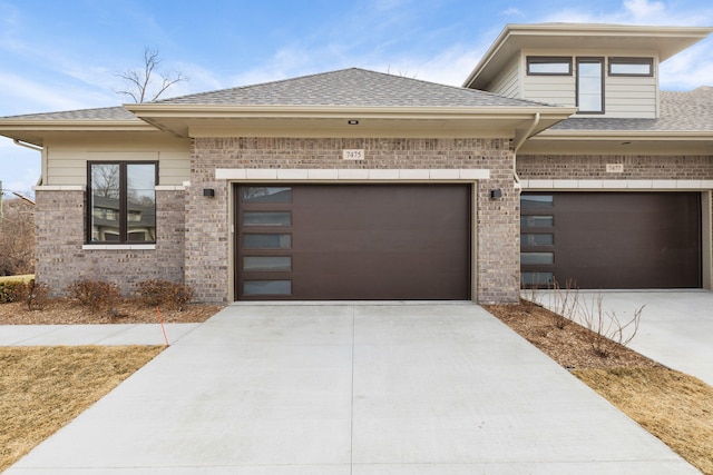 prairie-style home with brick siding, driveway, and a shingled roof