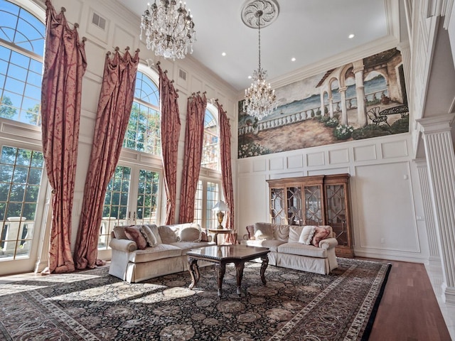 living area featuring a chandelier, a decorative wall, crown molding, and a high ceiling
