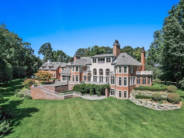 back of property featuring a chimney and a yard