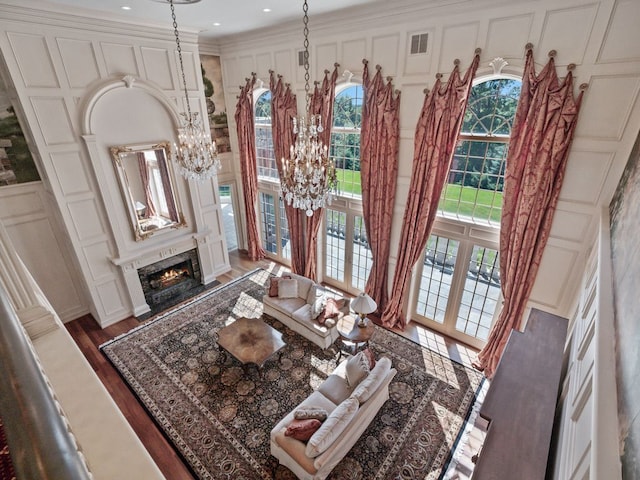 living room with visible vents, a chandelier, a premium fireplace, wood finished floors, and a decorative wall