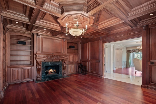 unfurnished living room featuring built in features, a notable chandelier, wood ceiling, and wooden walls