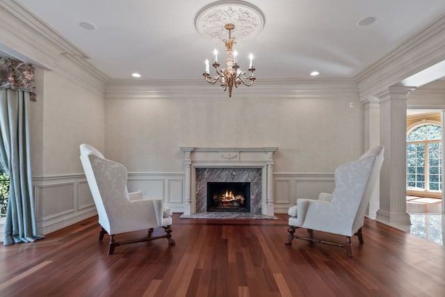 sitting room with an inviting chandelier, a decorative wall, wood finished floors, and a high end fireplace