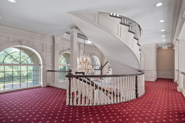 stairway featuring carpet, a chandelier, ornamental molding, recessed lighting, and a decorative wall