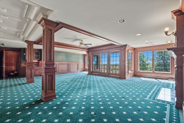 interior space featuring carpet floors, ornate columns, ornamental molding, a decorative wall, and a ceiling fan