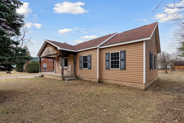 view of front facade with covered porch, a front lawn, and a shingled roof