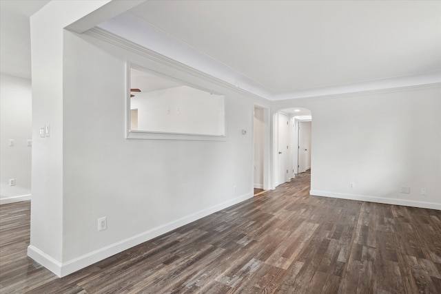 unfurnished room featuring baseboards, arched walkways, wood finished floors, and ornamental molding