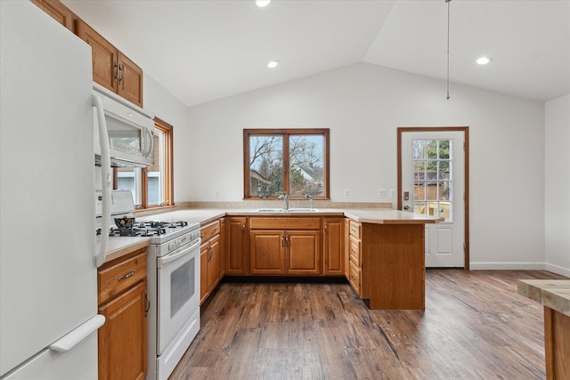 kitchen with a sink, white appliances, a peninsula, dark wood-style flooring, and vaulted ceiling